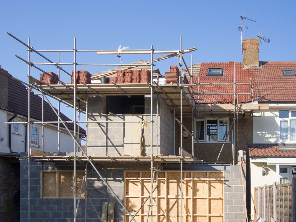 Une maison résidentielle en construction avec un échafaudage visible, illustrant les aspects pratiques de la régularisation des constructions dans le développement urbain.