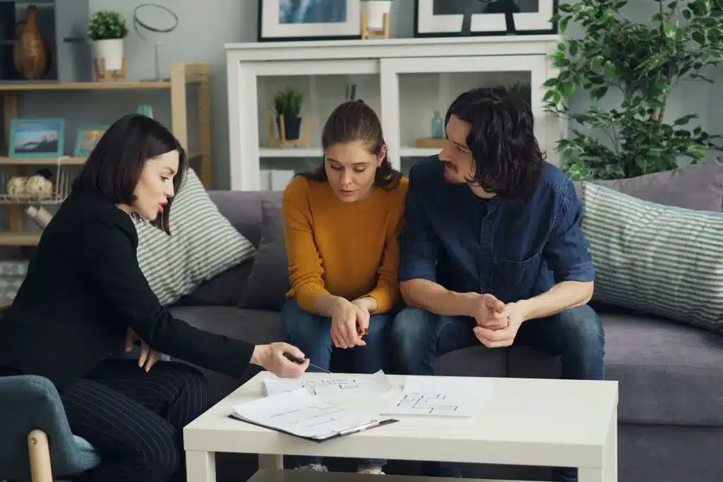 Avocate montrant des plans de construction à un couple, autour d'une table basse