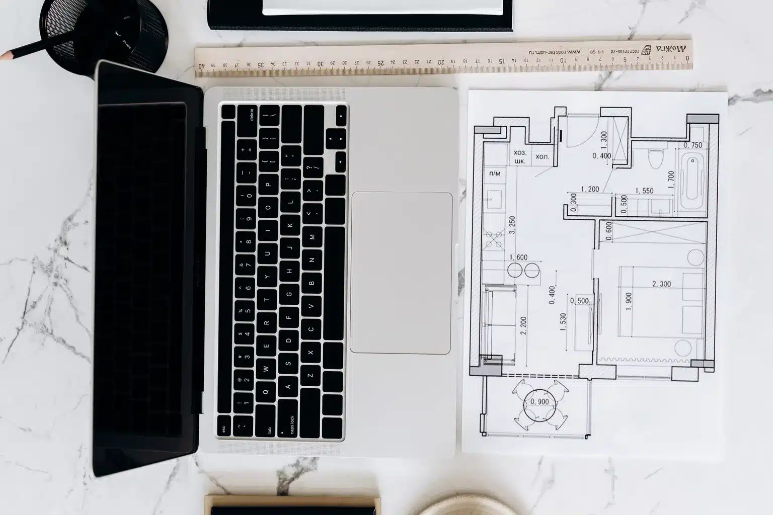 Préparer son permis de construire avec l’IA Plan d'appartement imprimé posé à côté d'un ordinateur portable ouvert, avec une règle, sur un bureau